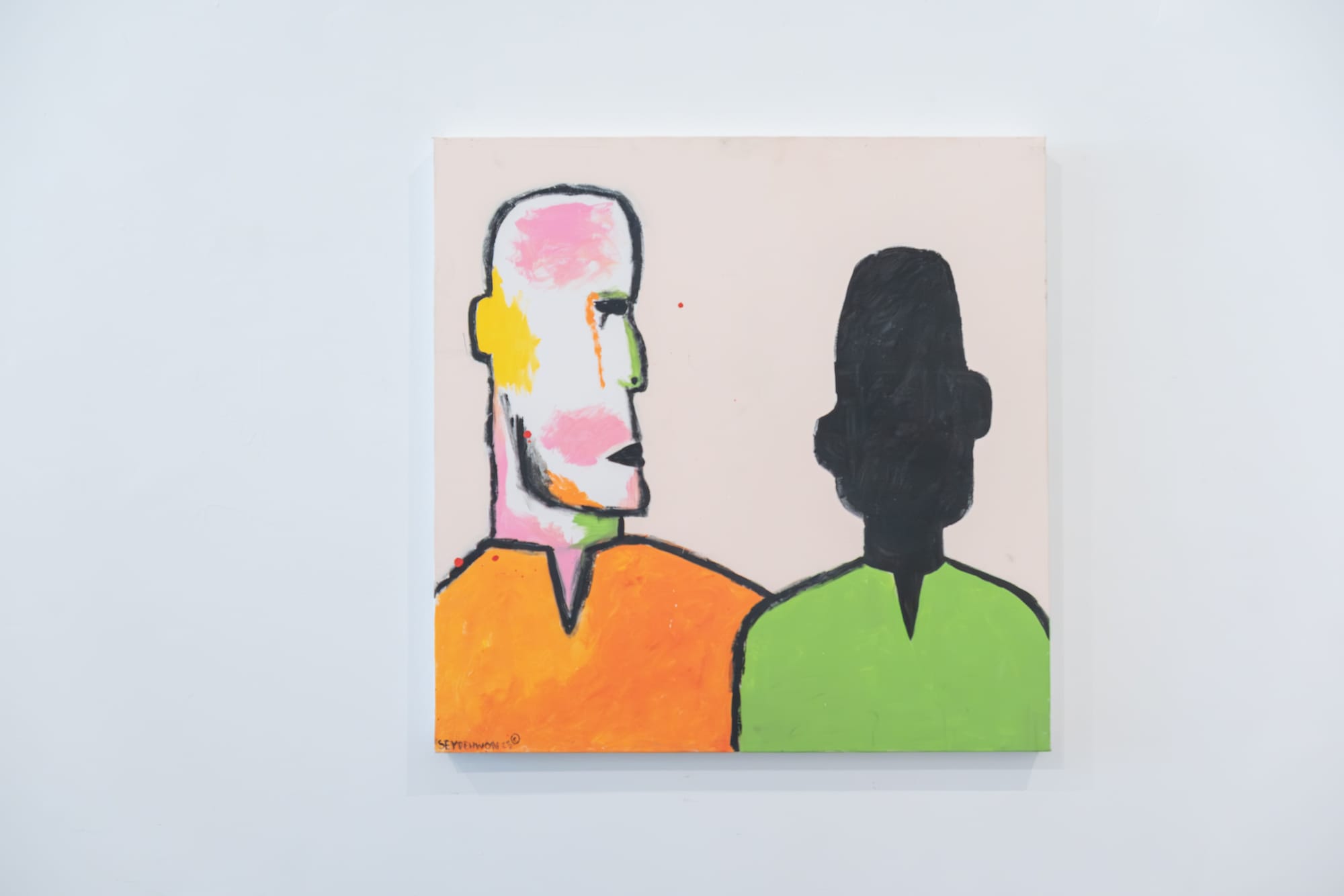 A painting hangs on a white wall depicting two figures abstracted through black shadows and bursts of color.